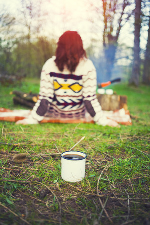 Coffee mug standing on the grass in a Park with a girl resting in the background.の写真素材