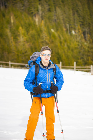 Climber with backpack and walking sticks is the snowy slope.の写真素材