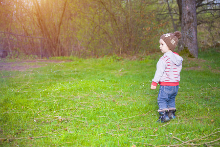 A boy with curly blond hair and stands on the gravel.の写真素材