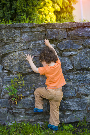 A boy with curly blond hair and stands on the gravel.の写真素材
