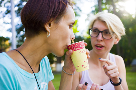 Girls having fun in the Park and drink coffee.の写真素材