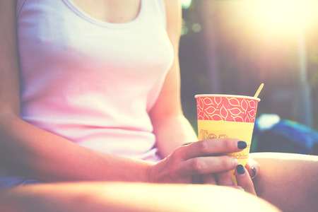 Girl drinking coffee sitting on the street in the Park.の写真素材