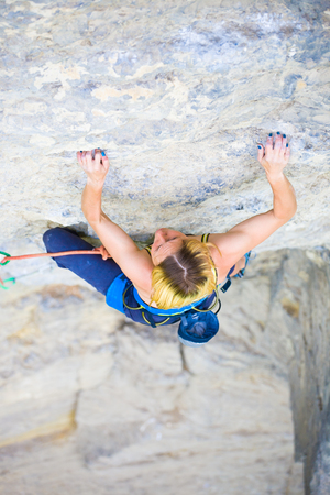 Strong girl climbs on a rock, doing sports climbing in nature.の写真素材
