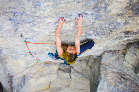Strong girl climbs on a rock, doing sports climbing in nature.の写真素材