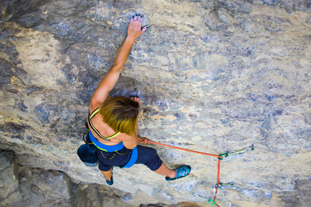 Strong girl climbs on a rock, doing sports climbing in nature.の写真素材