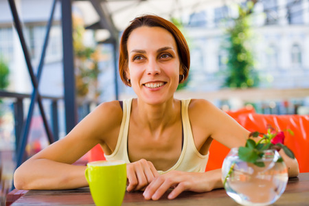 Beautiful and young girl sitting at a table in the coffee shop and laughing.の写真素材