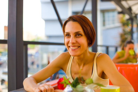 Beautiful and young girl sitting at a table in the coffee shop and laughing.の写真素材