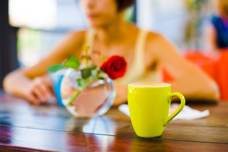 Cup of cappuccino stands on a wooden table in summer cafe. Girl drinking cappuccino.の写真素材