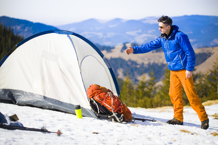 Climber stands near the tent with a backpack and holds the hand of his friend.の写真素材