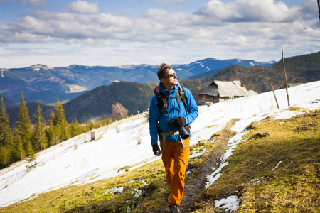 A traveler with a backpack and a camera travels through the mountains.の写真素材