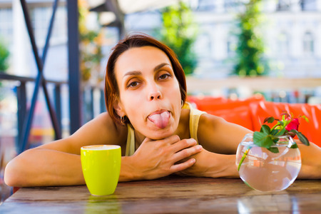 The girl sitting at the table extending a hand forward and drink the drink.の写真素材
