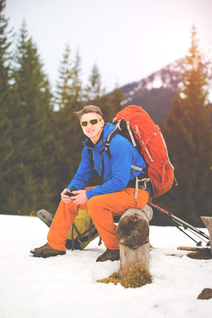 Hiker with backpack resting on a halt and to use the phone.の写真素材