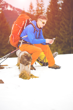Hiker with backpack resting on a halt and to use the phone.の写真素材