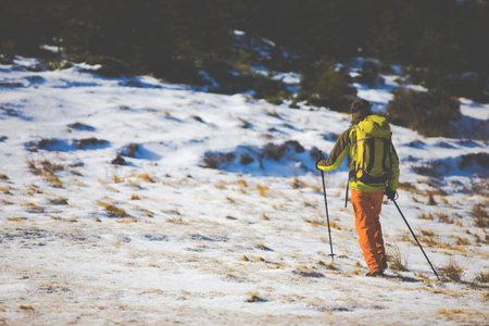 Hiker with backpack goes on the track. Journey through the winter mountains.