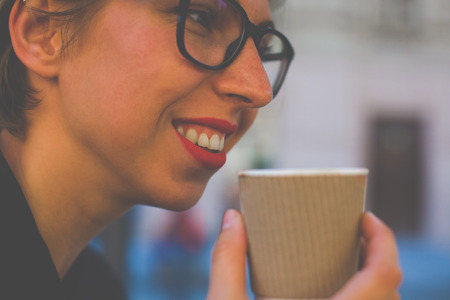 Girl drinking a beverage from a disposable Cup. Light toning.の写真素材