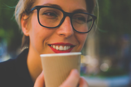 Girl drinking a beverage from a disposable Cup. Light toning.の写真素材