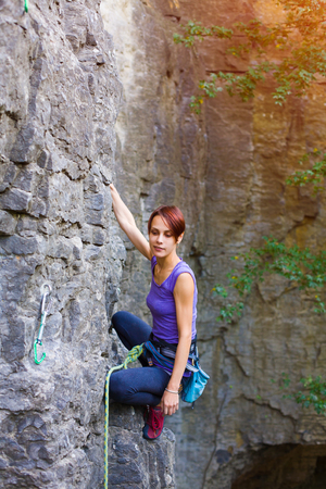 A young woman with a rope engaged in the sports of rock climbing on the rock.の写真素材