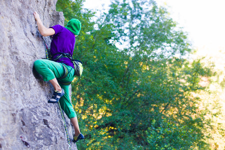 A young woman with a rope engaged in the sports of rock climbing on the rock.の写真素材