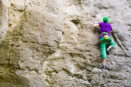 A young woman with a rope engaged in the sports of rock climbing on the rock.の写真素材