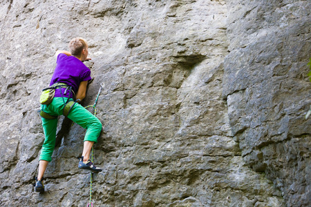 A young woman with a rope engaged in the sports of rock climbing on the rock.の写真素材