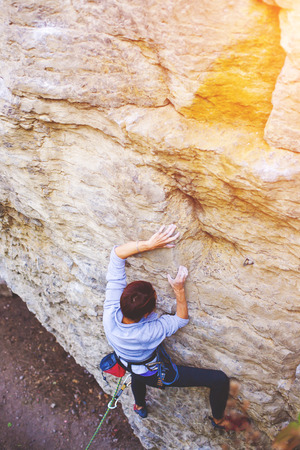 A young woman with a rope engaged in the sports of rock climbing on the rock.の写真素材