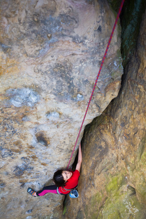 Girl rock climber climbs difficult route on the cliffs.の写真素材