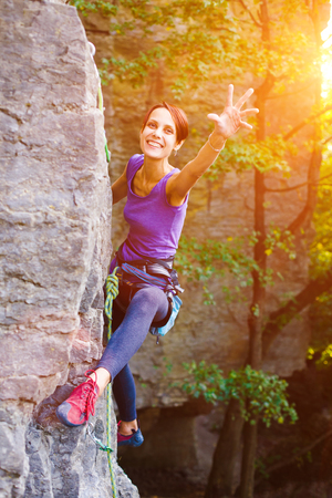 A young woman with a rope engaged in the sports of rock climbing on the rock.の写真素材