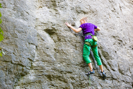 A young woman with a rope engaged in the sports of rock climbing on the rock.の写真素材