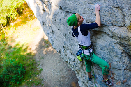 A young woman with a rope engaged in the sports of rock climbing on the rock.の写真素材