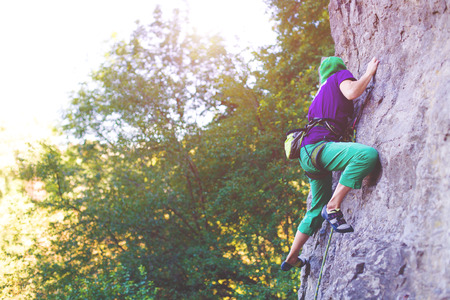 A young woman with a rope engaged in the sports of rock climbing on the rock.の写真素材