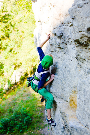 A young woman with a rope engaged in the sports of rock climbing on the rock.の写真素材