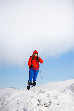 girl with backpack walking on snow in the mountains and mountain climbing during the winter holidays.の写真素材