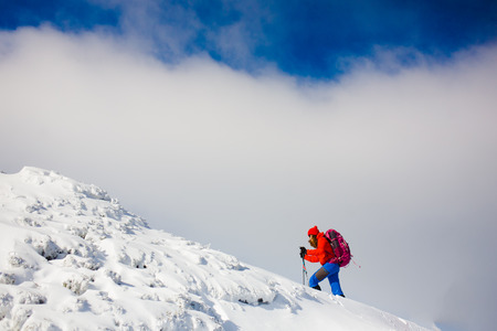 climber with backpack walks on a snowy slope on a blue sky background, winter holidays in the mountains.の写真素材