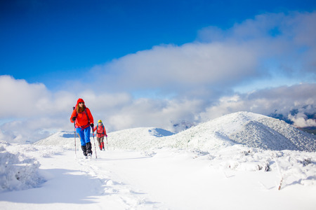 Two girls go on a snowy hill during a mountaineering adventure in the mountains.の写真素材
