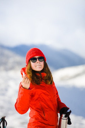 girl climber uses chapstick in the mountains in winter, hygiene during the winter holidays in the mountains.の写真素材