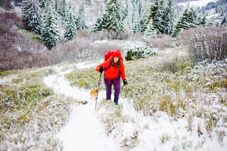 girl with backpack walking on snow in the mountains and mountain climbing during the winter holidays.の写真素材
