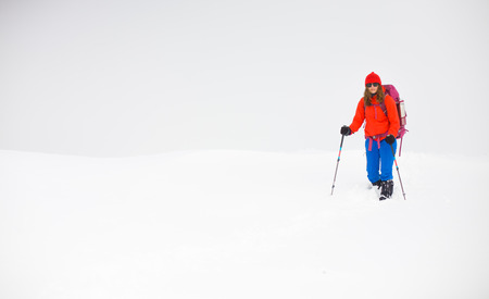 girl with backpack walking on snow in the mountains and mountain climbing during the winter holidays.の写真素材