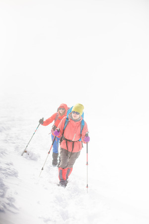 two girls are climbing the mountain during a snow storm. bad weather in the mountains.の写真素材