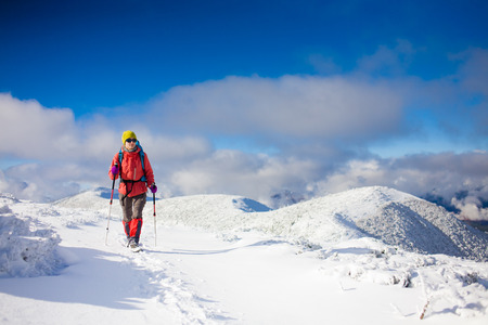 girl with backpack walking on snow in the mountains and mountain climbing during the winter holidays.の写真素材