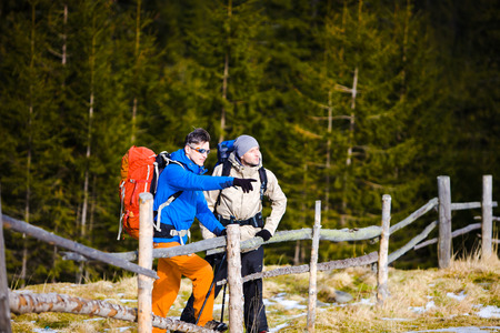 The other two tourists with backpacks to discuss the route of a hike in the mountains.の写真素材