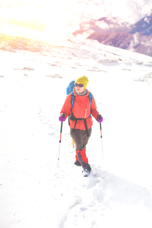 girl with backpack walking on snow in the mountains and mountain climbing during the winter holidays.の写真素材