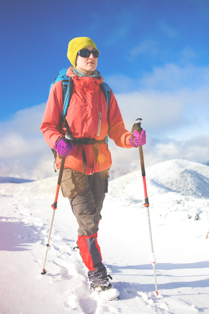 girl with backpack walking on snow in the mountains and mountain climbing during the winter holidays.の写真素材