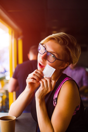 young girl holding a packet of sugar sitting in a cafe.
の写真素材