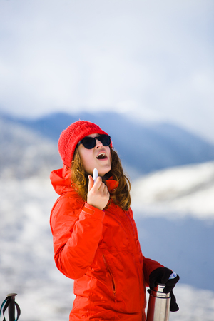 girl climber uses chapstick in the mountains in winter, hygiene during the winter holidays in the mountains.の写真素材