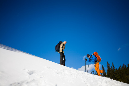 two climbers on a snow slope in the mountains, climbing to the top of the mountain in winter.の写真素材
