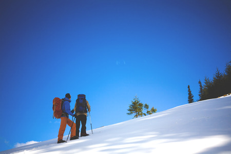 two climbers on a snow slope in the mountains, climbing to the top of the mountain in winter.の写真素材