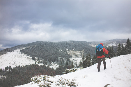 girl with backpack walking on snow in the mountains and mountain climbing during the winter holidays.の写真素材