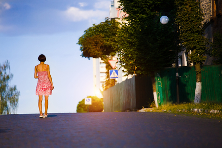 woman in a summer dress standing on the road and looks into the distance.の写真素材