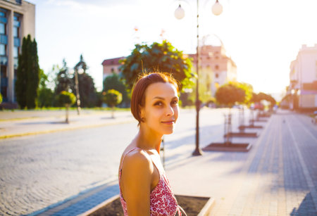 young woman standing on a city street, portrait of a girl on a background of urban buildings.の写真素材