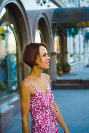 young woman standing on a city street, portrait of a girl on a background of urban buildings.の写真素材